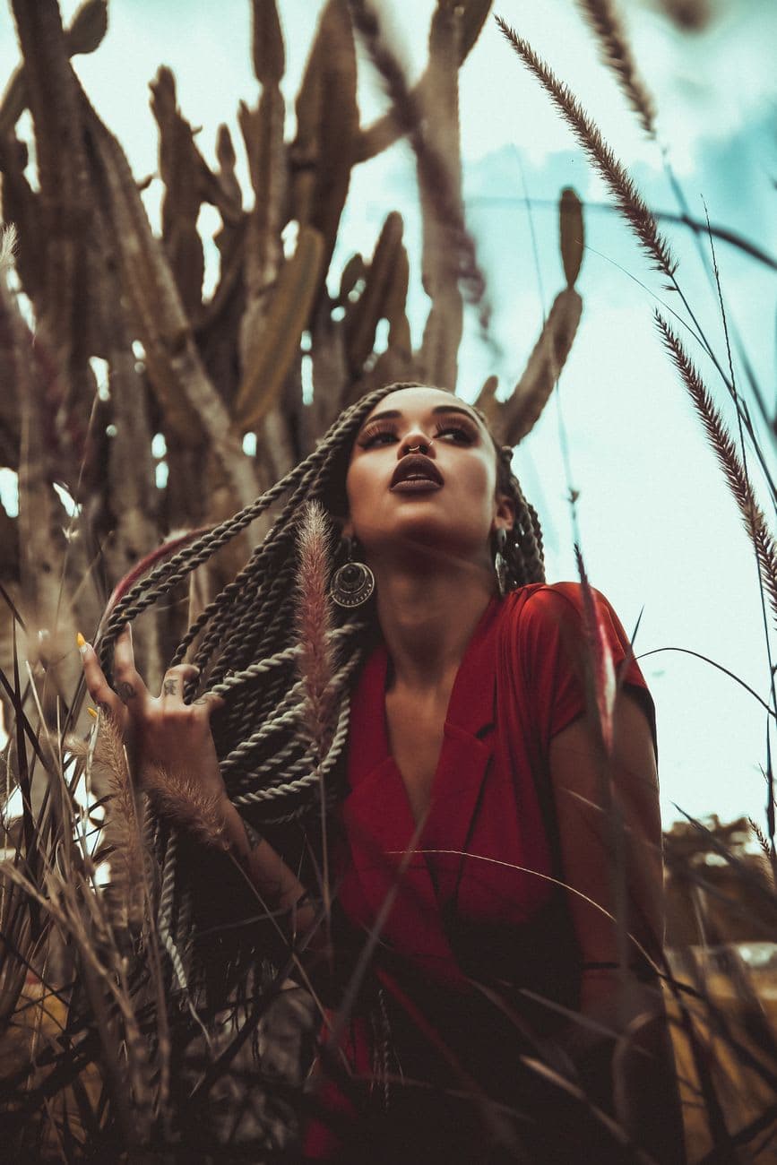 African American woman posing among desert cacti, showcasing fashion and natural beauty.