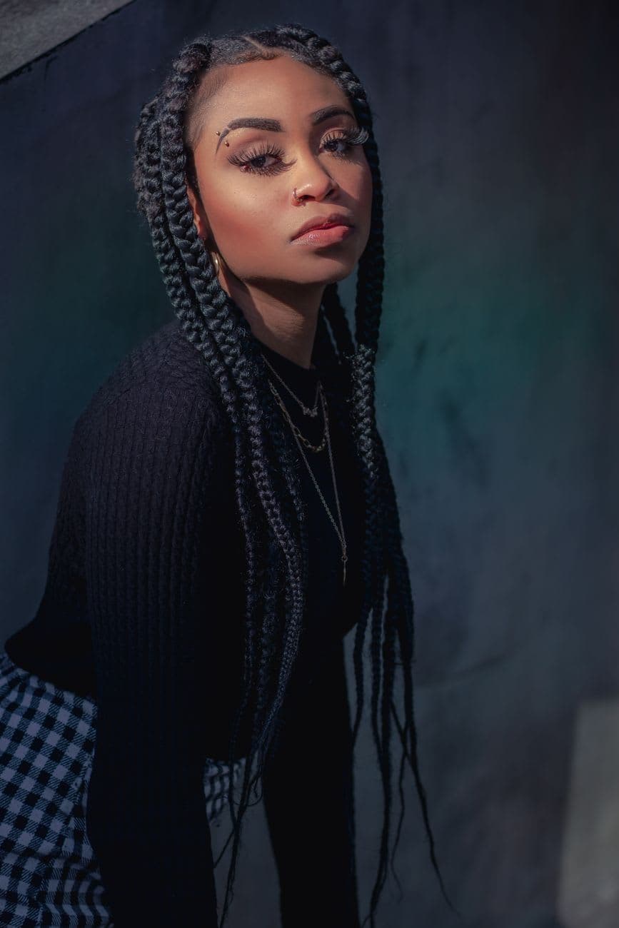 Elegant portrait of a young woman with braided hair in stylish black attire.