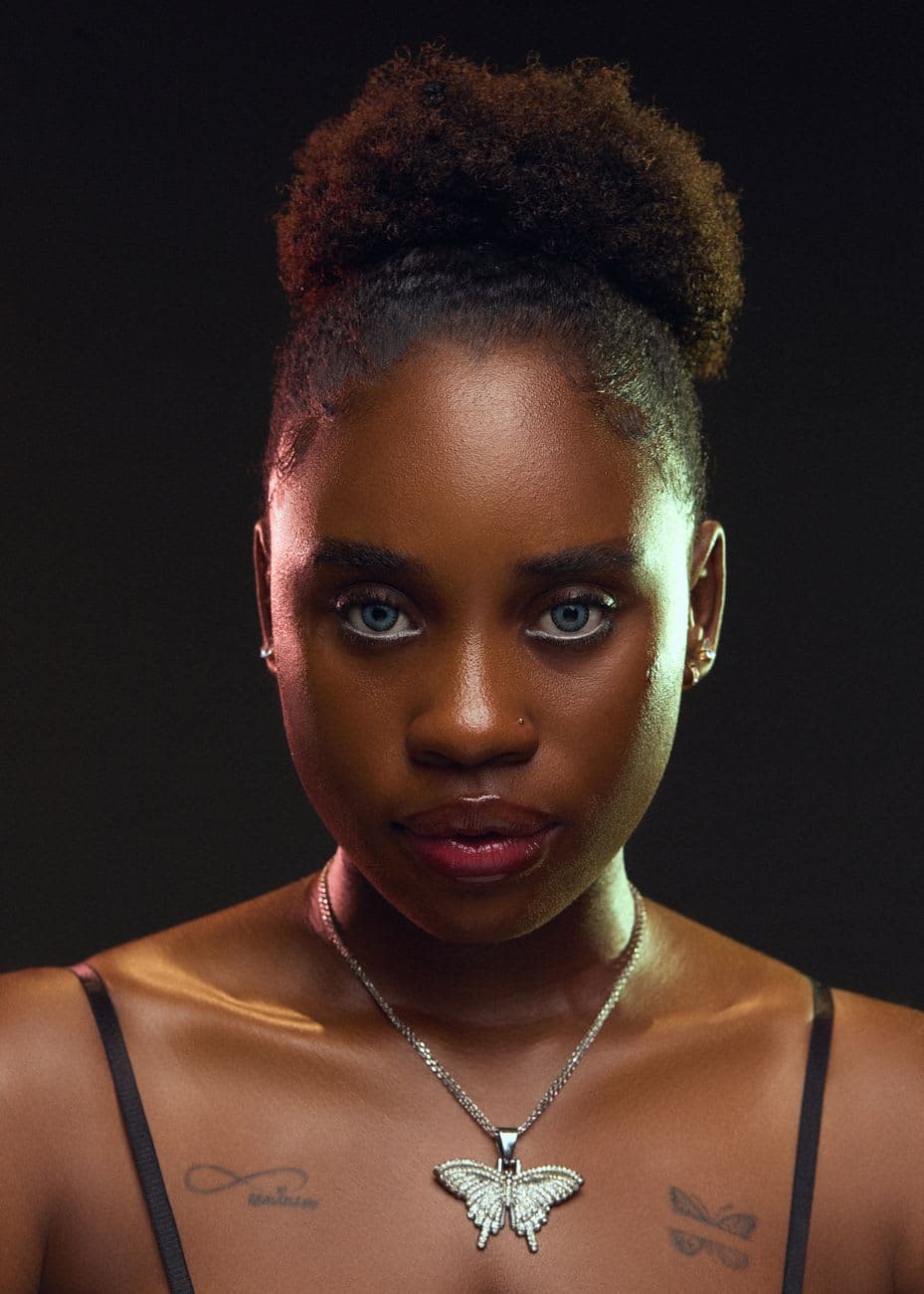 Close-up portrait of a woman with a butterfly necklace, dramatic lighting.