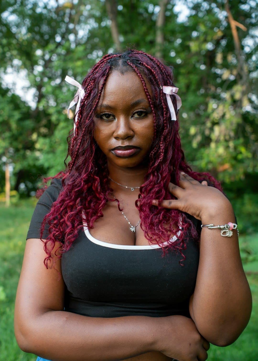A woman poses with pink hair in nature.