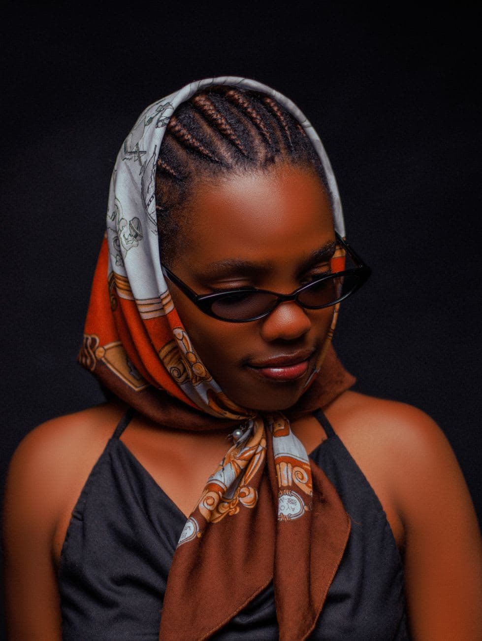 Stylish portrait of a woman in Nairobi showcasing African fashion with a scarf and sunglasses.