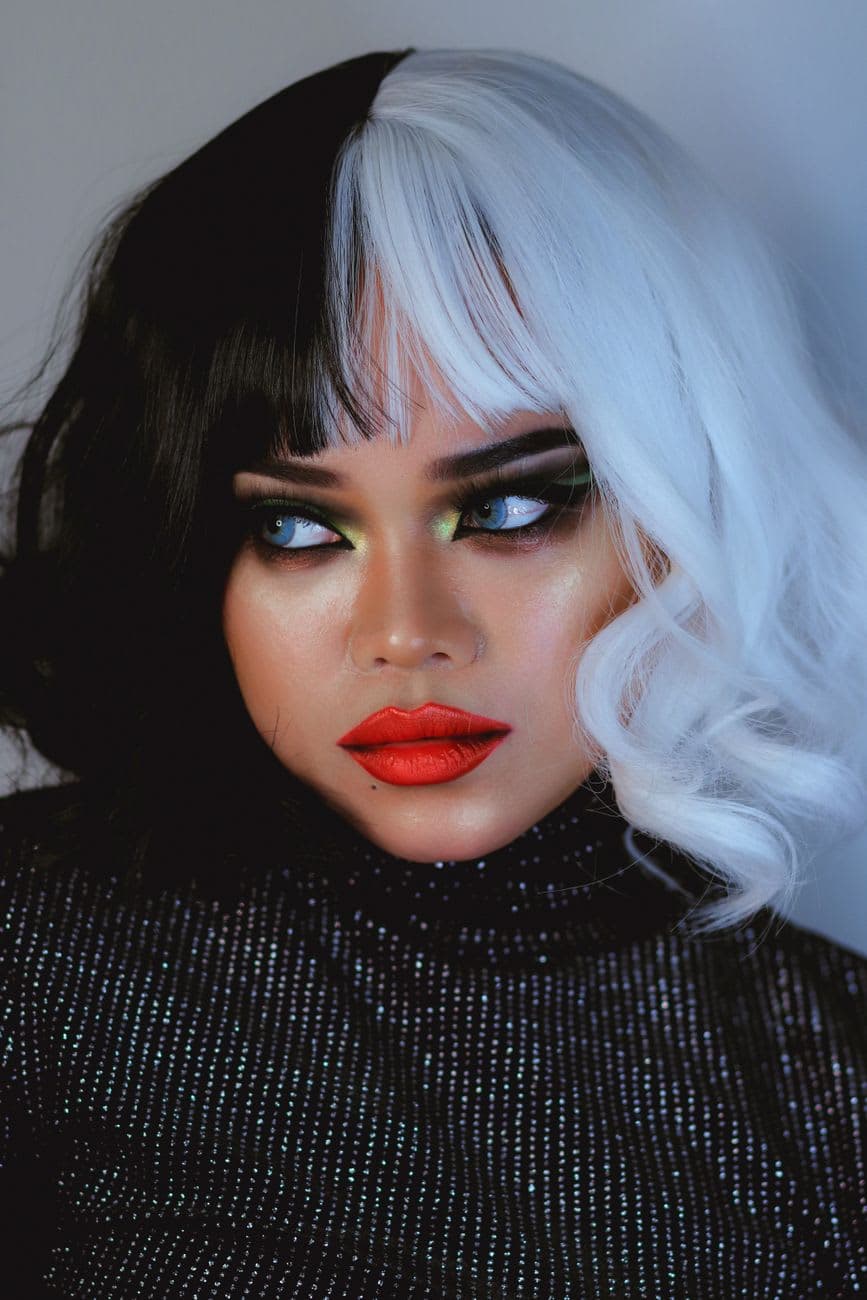 Striking portrait featuring bold makeup and black-and-white hair, showcasing artistic expression.
