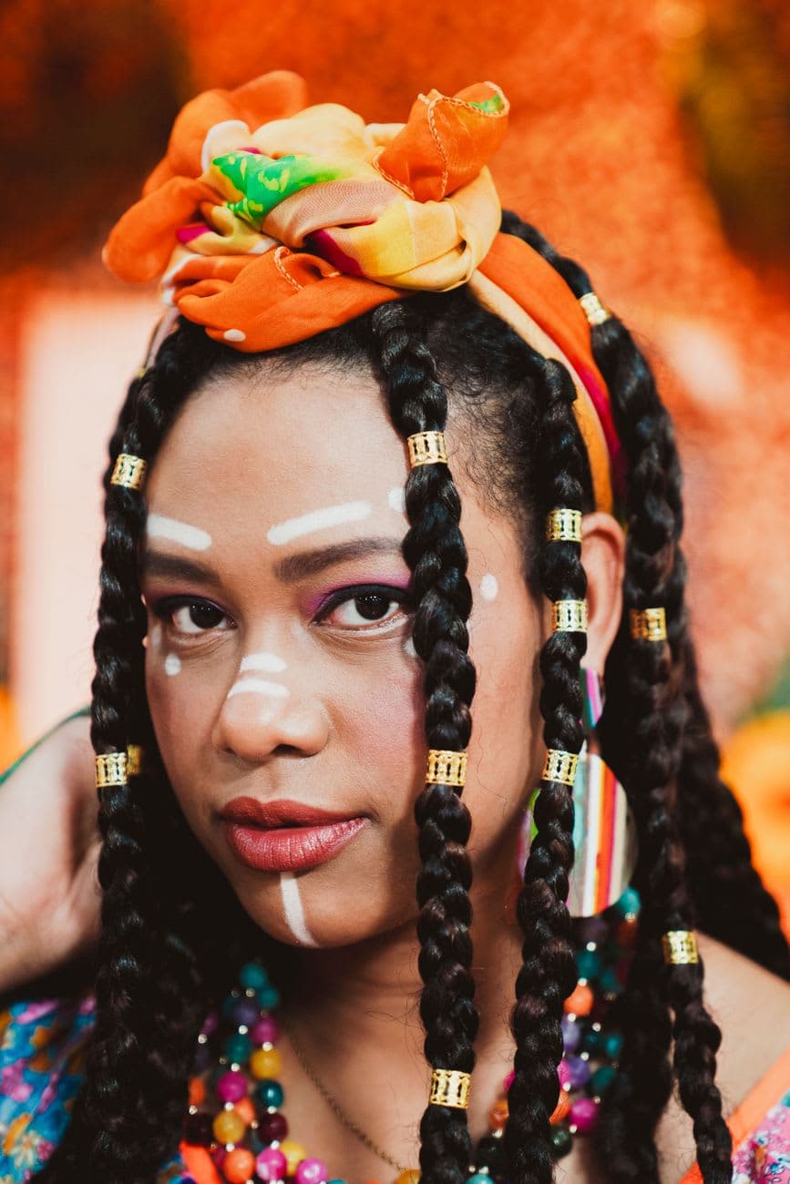 Vibrant portrait featuring a woman with tribal makeup and braided hair, exuding bold cultural expression.