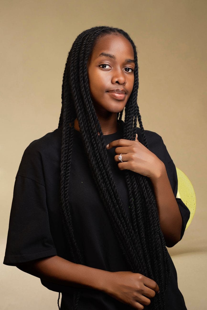 Elegant portrait of a young African woman with long braided hair against a neutral backdrop.