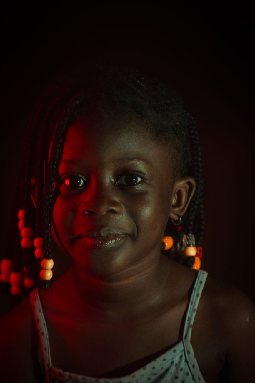 Close-up portrait of a smiling young girl with braided hair and colorful beads.