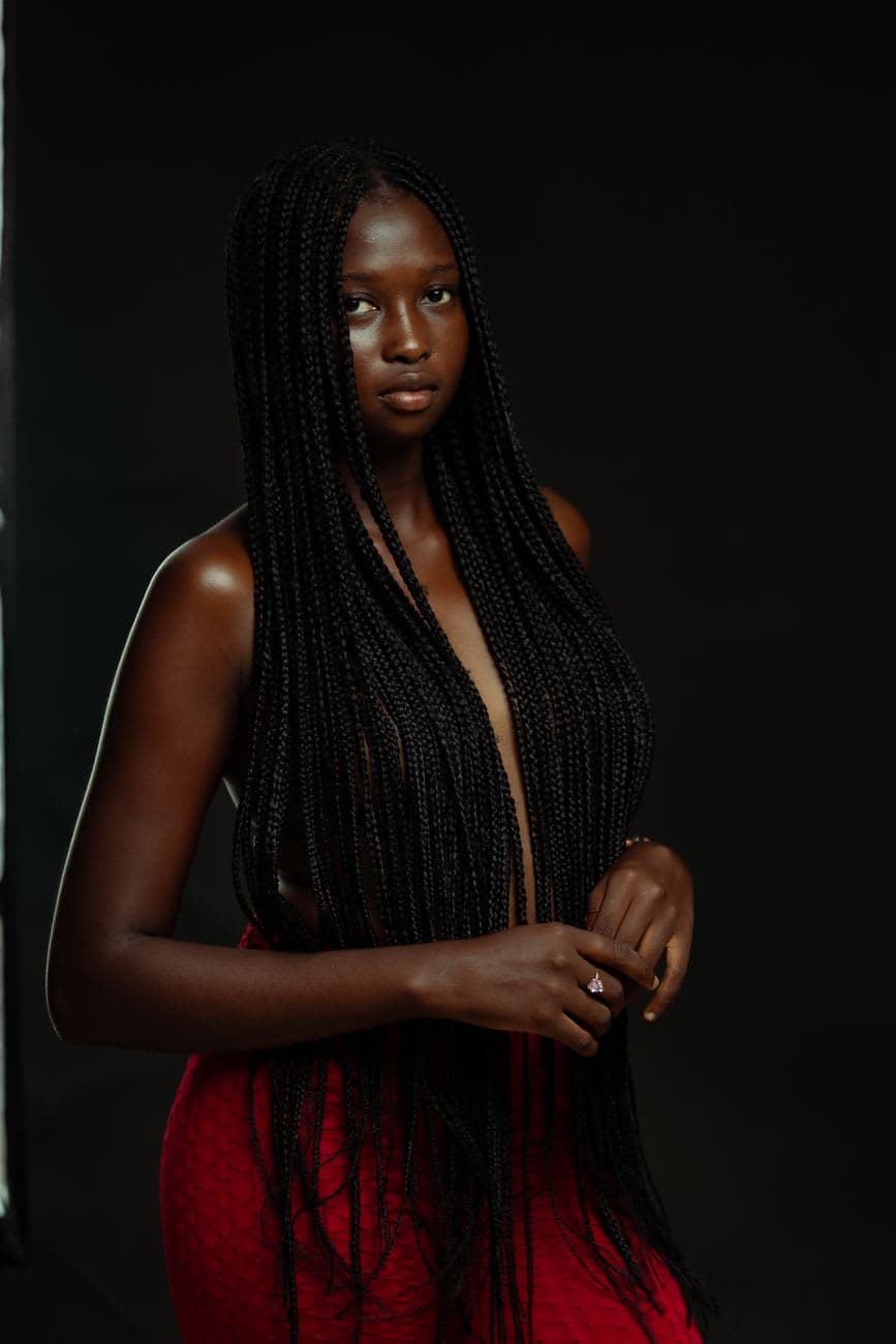 Captivating portrait of a woman with long braided hair against a dark background.