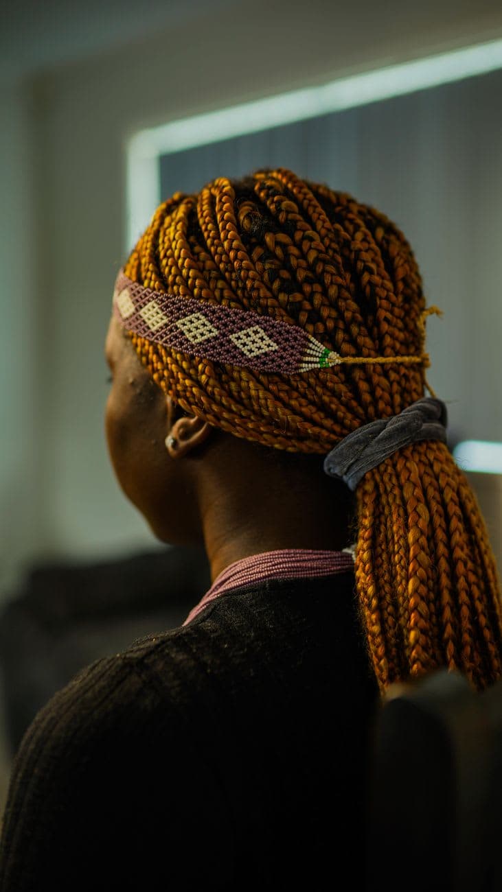 Close-up of a woman with braided hair and headband, showcasing cultural style.