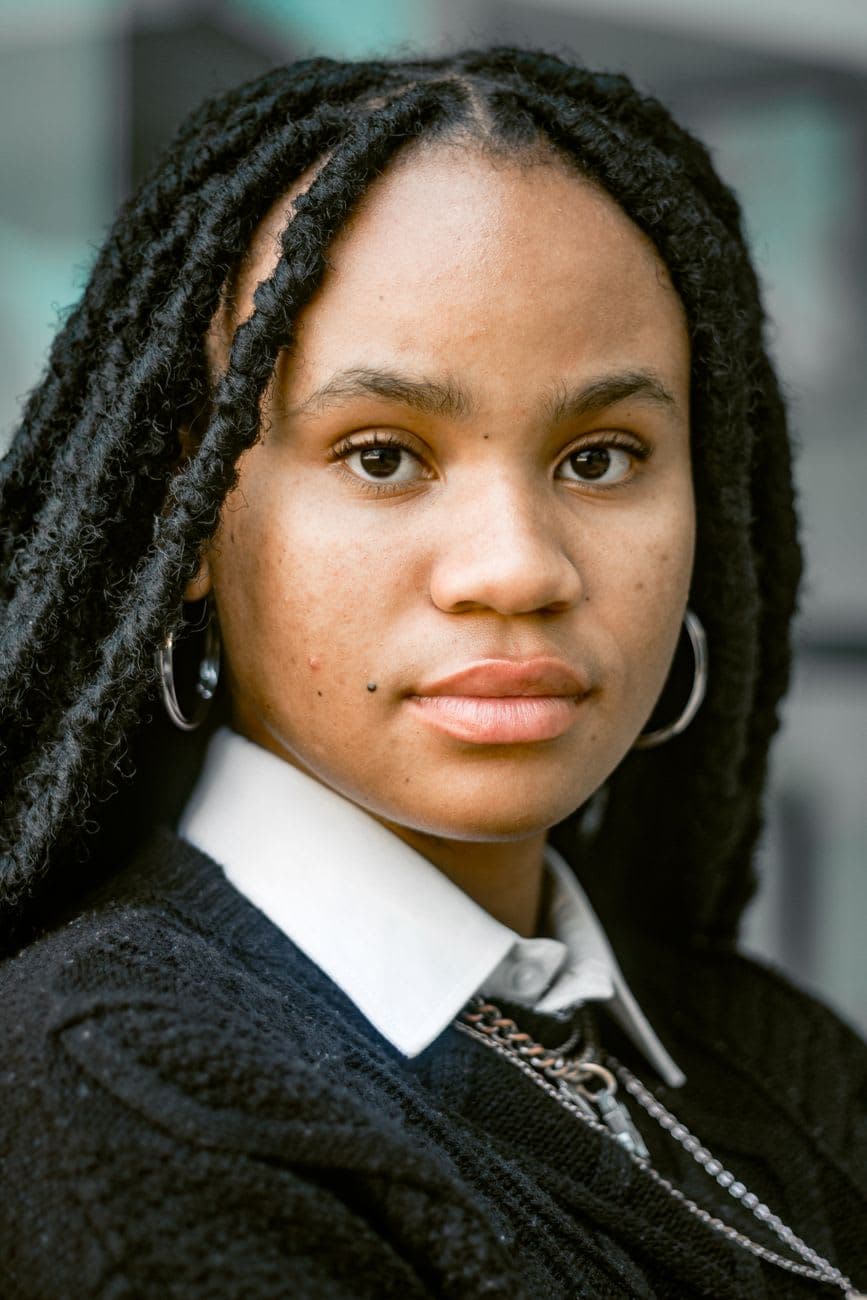 Close-up portrait of an adult woman with dreadlocks and hoop earrings.