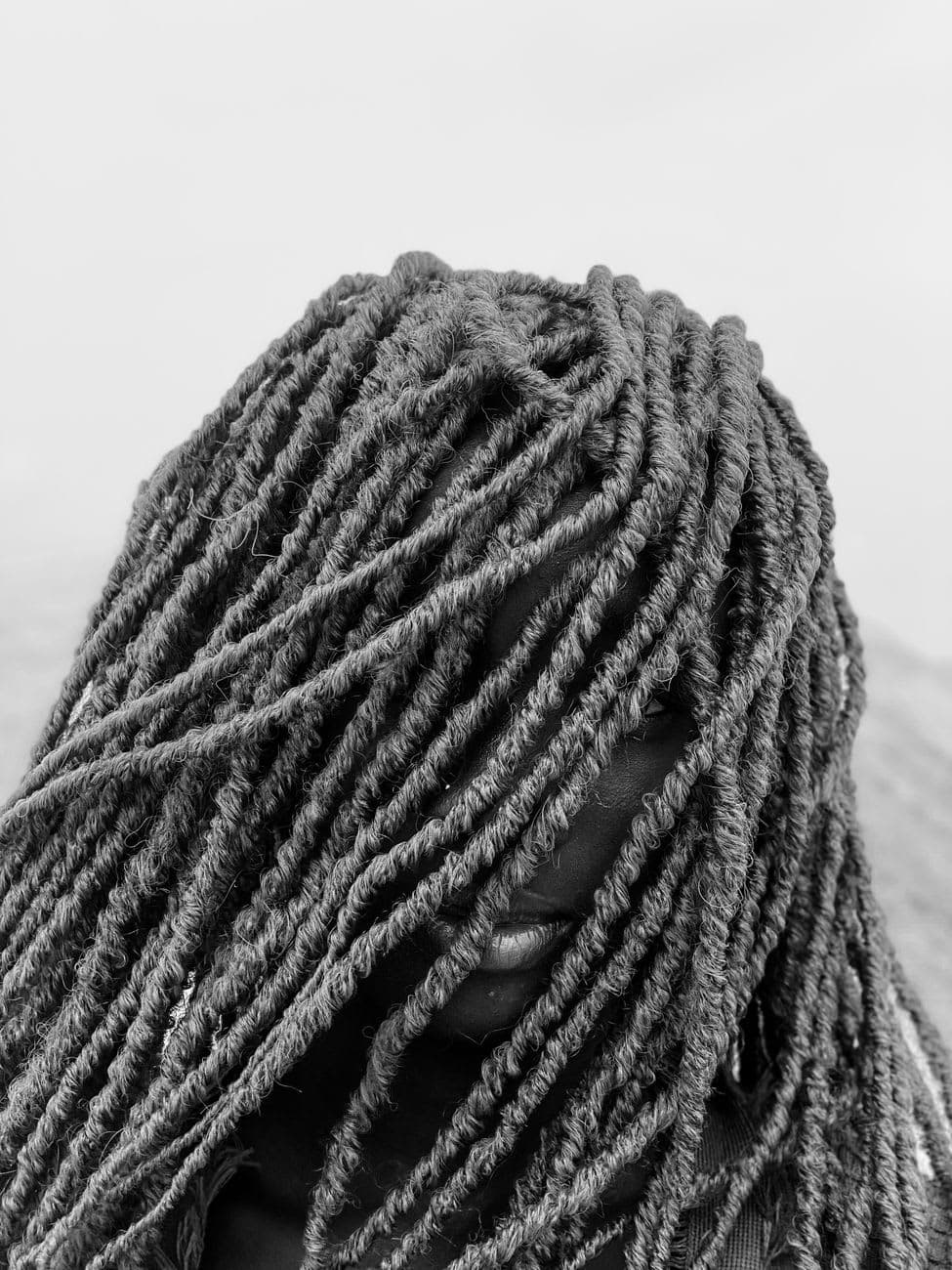 Artistic black and white portrait focusing on thick dreadlocks, captured outdoors in Lagos.