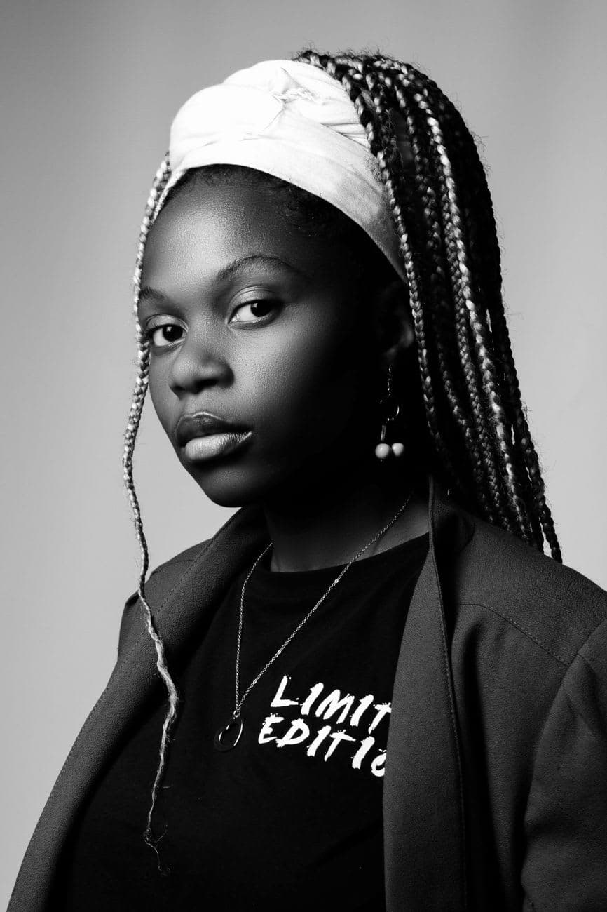 Elegant black and white portrait of a young woman with locs, wearing a headband and jewelry.