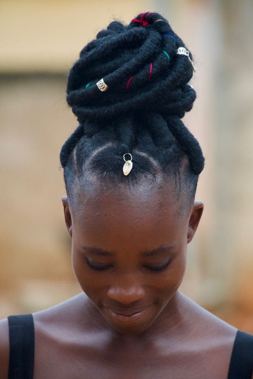 A woman in Kumasi, Ghana, showcasing a trendy dreadlocks hairstyle with an updo. Captured outdoors.