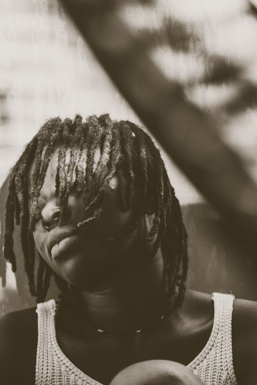 Emotive black and white portrait of a woman with dreadlocks expressing contemplation.
