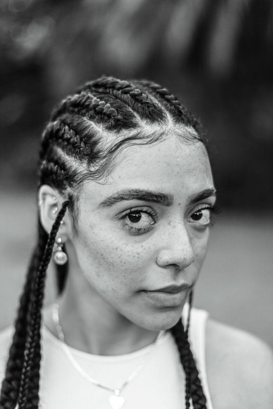 Close-up black and white portrait of a woman with braided hair, showcasing natural beauty and confidence.