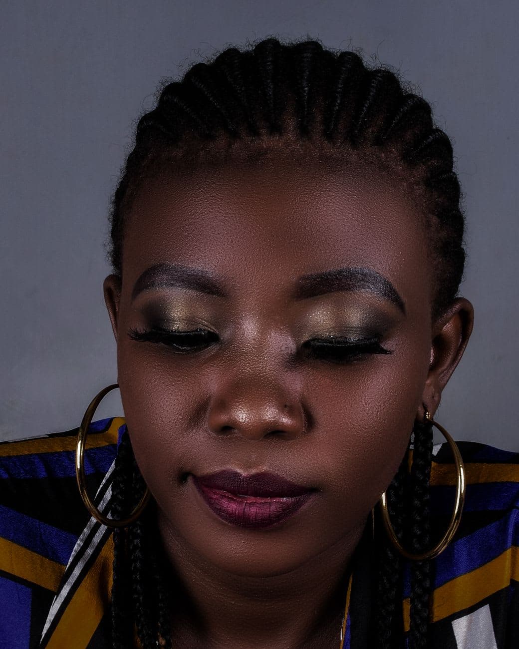 Graceful portrait of a woman with braided hair and subtle makeup, showcasing elegance.